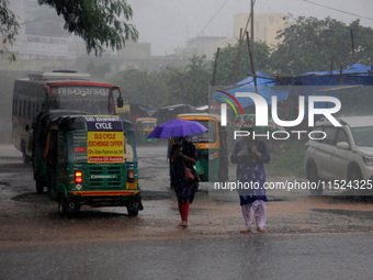 Pedestrians and commuters are seen on the road as it rains in Bhubaneswar, the capital city of the eastern Indian state of Odisha. Rain lash...