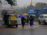 Pedestrians and commuters are seen on the road as it rains in Bhubaneswar, the capital city of the eastern Indian state of Odisha. Rain lash...