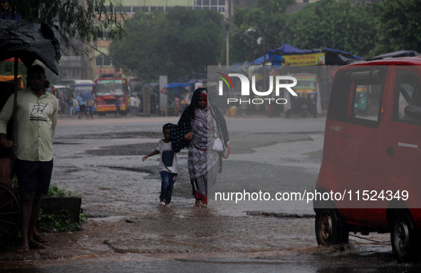 Pedestrians and commuters are seen on the road as it rains in Bhubaneswar, the capital city of the eastern Indian state of Odisha. Rain lash...