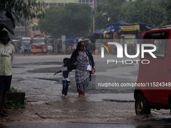 Pedestrians and commuters are seen on the road as it rains in Bhubaneswar, the capital city of the eastern Indian state of Odisha. Rain lash...