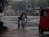 Pedestrians and commuters are seen on the road as it rains in Bhubaneswar, the capital city of the eastern Indian state of Odisha. Rain lash...