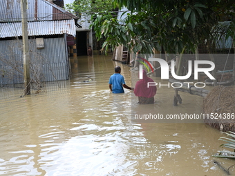 People walk in flood water in Feni District, Bangladesh, on August 29, 2024. At least 52 people are killed, a total of 43 upazilas in severa...