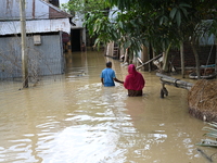 People walk in flood water in Feni District, Bangladesh, on August 29, 2024. At least 52 people are killed, a total of 43 upazilas in severa...