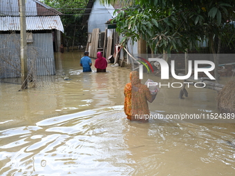 People walk in flood water in Feni District, Bangladesh, on August 29, 2024. At least 52 people are killed, a total of 43 upazilas in severa...