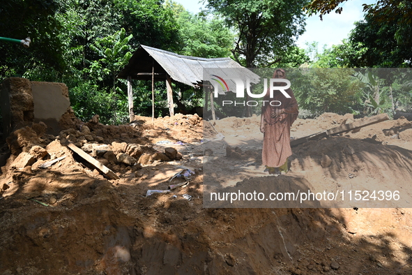 People stand in their broken house by flood water in Feni District, Bangladesh, on August 29, 2024. At least 52 people are killed, a total o...