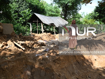 People stand in their broken house by flood water in Feni District, Bangladesh, on August 29, 2024. At least 52 people are killed, a total o...