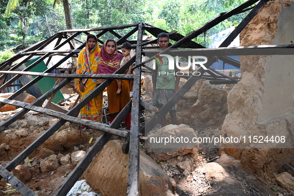 People stand in their broken house by flood water in Feni District, Bangladesh, on August 29, 2024. At least 52 people are killed, a total o...