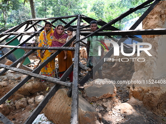 People stand in their broken house by flood water in Feni District, Bangladesh, on August 29, 2024. At least 52 people are killed, a total o...