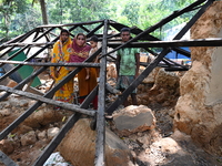 People stand in their broken house by flood water in Feni District, Bangladesh, on August 29, 2024. At least 52 people are killed, a total o...