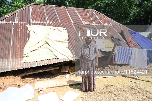 People stand in their broken house by flood water in Feni District, Bangladesh, on August 29, 2024. At least 52 people are killed, a total o...