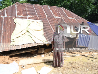 People stand in their broken house by flood water in Feni District, Bangladesh, on August 29, 2024. At least 52 people are killed, a total o...