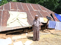 People stand in their broken house by flood water in Feni District, Bangladesh, on August 29, 2024. At least 52 people are killed, a total o...