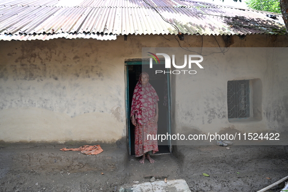 People stand in their broken house by flood water in Feni District, Bangladesh, on August 29, 2024. At least 52 people are killed, a total o...