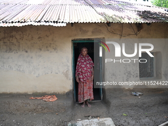 People stand in their broken house by flood water in Feni District, Bangladesh, on August 29, 2024. At least 52 people are killed, a total o...