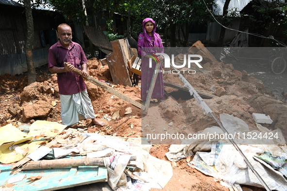 People stand in their broken house by flood water in Feni District, Bangladesh, on August 29, 2024. At least 52 people are killed, a total o...