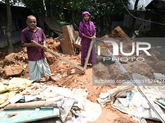 People stand in their broken house by flood water in Feni District, Bangladesh, on August 29, 2024. At least 52 people are killed, a total o...