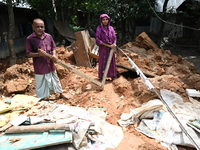 People stand in their broken house by flood water in Feni District, Bangladesh, on August 29, 2024. At least 52 people are killed, a total o...