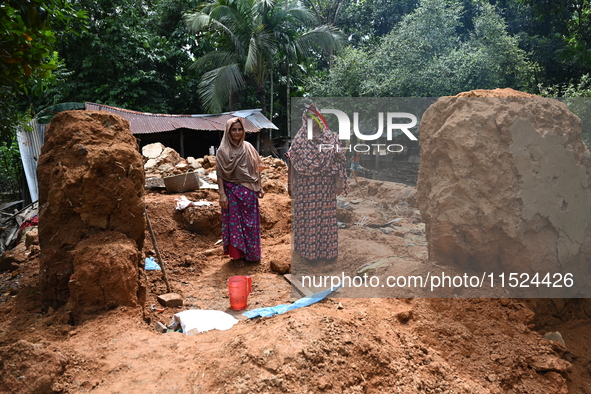 People stand in their broken house by flood water in Feni District, Bangladesh, on August 29, 2024. At least 52 people are killed, a total o...