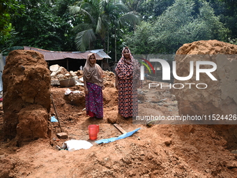 People stand in their broken house by flood water in Feni District, Bangladesh, on August 29, 2024. At least 52 people are killed, a total o...