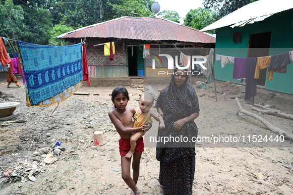 People stand in their broken house by flood water in Feni District, Bangladesh, on August 29, 2024. At least 52 people are killed, a total o...