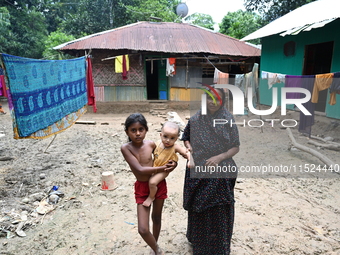 People stand in their broken house by flood water in Feni District, Bangladesh, on August 29, 2024. At least 52 people are killed, a total o...