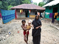 People stand in their broken house by flood water in Feni District, Bangladesh, on August 29, 2024. At least 52 people are killed, a total o...