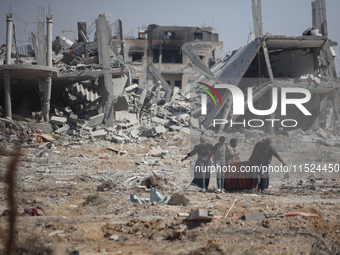 Palestinians collect their belongings and inspect the destruction caused by Israeli airstrikes in eastern Deir al-Balah in central Gaza Stri...