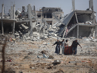 Palestinians collect their belongings and inspect the destruction caused by Israeli airstrikes in eastern Deir al-Balah in central Gaza Stri...