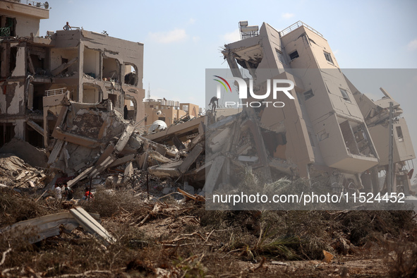 Palestinians collect their belongings and inspect the destruction caused by Israeli airstrikes in eastern Deir al-Balah in central Gaza Stri...