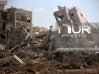 Palestinians collect their belongings and inspect the destruction caused by Israeli airstrikes in eastern Deir al-Balah in central Gaza Stri...