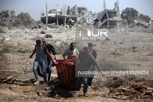 Palestinians collect their belongings and inspect the destruction caused by Israeli airstrikes in eastern Deir al-Balah in central Gaza Stri...