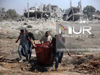 Palestinians collect their belongings and inspect the destruction caused by Israeli airstrikes in eastern Deir al-Balah in central Gaza Stri...