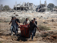 Palestinians collect their belongings and inspect the destruction caused by Israeli airstrikes in eastern Deir al-Balah in central Gaza Stri...