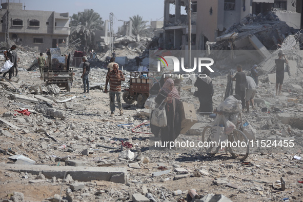 Palestinians collect their belongings and inspect the destruction caused by Israeli airstrikes in eastern Deir al-Balah in central Gaza Stri...