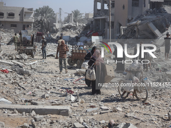 Palestinians collect their belongings and inspect the destruction caused by Israeli airstrikes in eastern Deir al-Balah in central Gaza Stri...