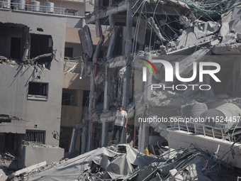 Palestinians collect their belongings and inspect the destruction caused by Israeli airstrikes in eastern Deir al-Balah in central Gaza Stri...