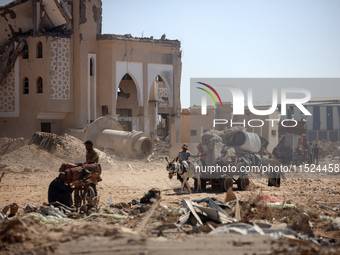 Palestinians collect their belongings and inspect the destruction caused by Israeli airstrikes in eastern Deir al-Balah in central Gaza Stri...