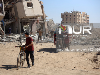 Palestinians collect their belongings and inspect the destruction caused by Israeli airstrikes in eastern Deir al-Balah in central Gaza Stri...