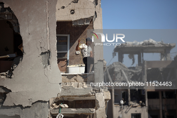 Palestinians collect their belongings and inspect the destruction caused by Israeli airstrikes in eastern Deir al-Balah in central Gaza Stri...