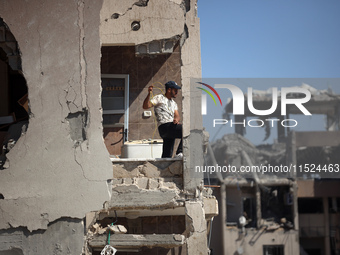 Palestinians collect their belongings and inspect the destruction caused by Israeli airstrikes in eastern Deir al-Balah in central Gaza Stri...