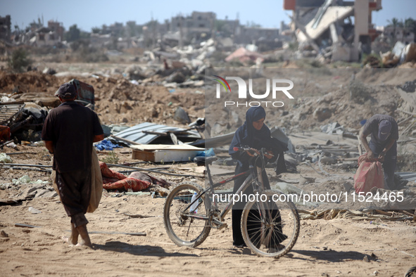 Palestinians collect their belongings and inspect the destruction caused by Israeli airstrikes in eastern Deir al-Balah in central Gaza Stri...