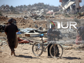 Palestinians collect their belongings and inspect the destruction caused by Israeli airstrikes in eastern Deir al-Balah in central Gaza Stri...