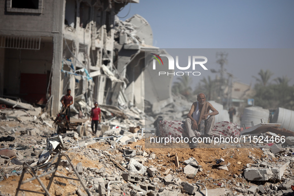 Palestinians collect their belongings and inspect the destruction caused by Israeli airstrikes in eastern Deir al-Balah in central Gaza Stri...