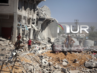 Palestinians collect their belongings and inspect the destruction caused by Israeli airstrikes in eastern Deir al-Balah in central Gaza Stri...