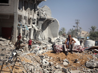 Palestinians collect their belongings and inspect the destruction caused by Israeli airstrikes in eastern Deir al-Balah in central Gaza Stri...