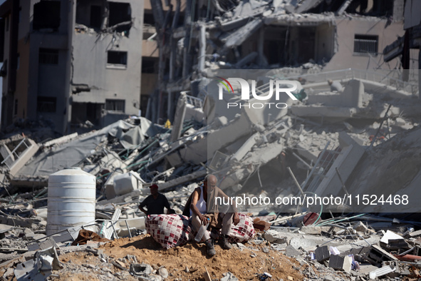 Palestinians collect their belongings and inspect the destruction caused by Israeli airstrikes in eastern Deir al-Balah in central Gaza Stri...