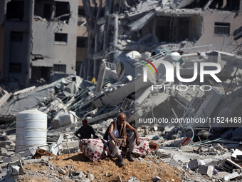 Palestinians collect their belongings and inspect the destruction caused by Israeli airstrikes in eastern Deir al-Balah in central Gaza Stri...