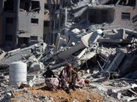 Palestinians collect their belongings and inspect the destruction caused by Israeli airstrikes in eastern Deir al-Balah in central Gaza Stri...