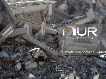 Palestinians collect their belongings and inspect the destruction caused by Israeli airstrikes in eastern Deir al-Balah in central Gaza Stri...