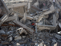 Palestinians collect their belongings and inspect the destruction caused by Israeli airstrikes in eastern Deir al-Balah in central Gaza Stri...